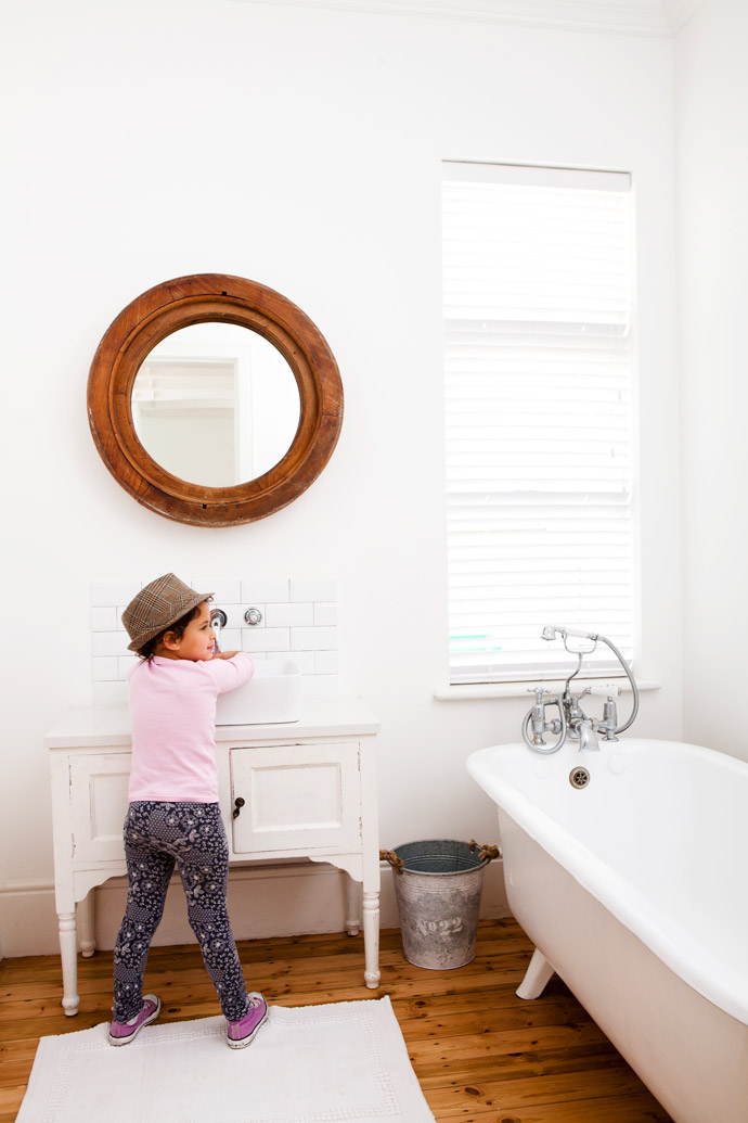 Mira washes her hands in the second bathroom. The striking mirror frame was this bathroom’s original Oregon pine window frame. Cara had a wash basin made from a cabinet, another Wynberg find. The metro tiles are from Tilehaus.
