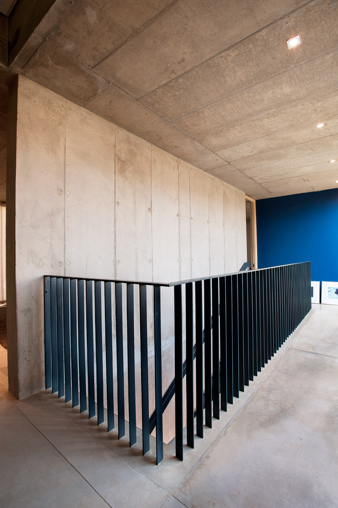 The elegant simplicity of the balustrade detail was created by casting the vertical steel flat bars of the balustrade directly into the concrete floor, creating a smooth and uncluttered finish. 