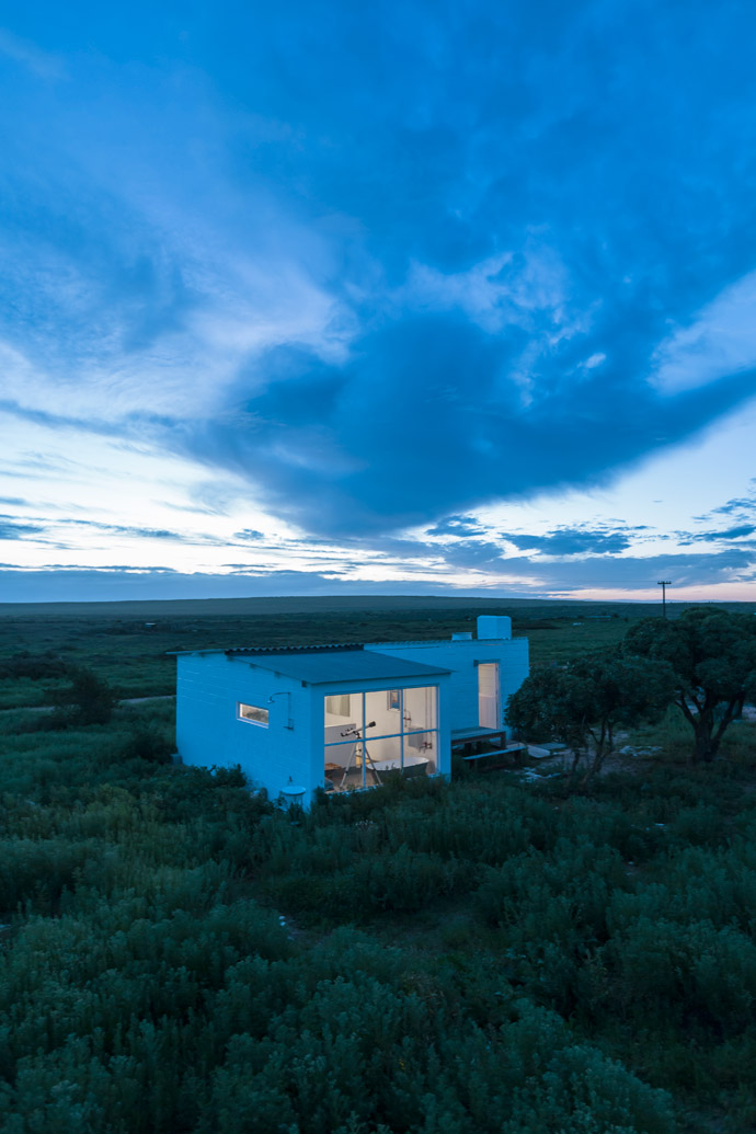 View to the north: The cottage glows like a tiny lightbox against the backdrop of the sky at sunset.