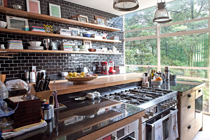 The warmth of the walnut cabinetry in the kitchen provides a striking contrast to the black subway tiles.
