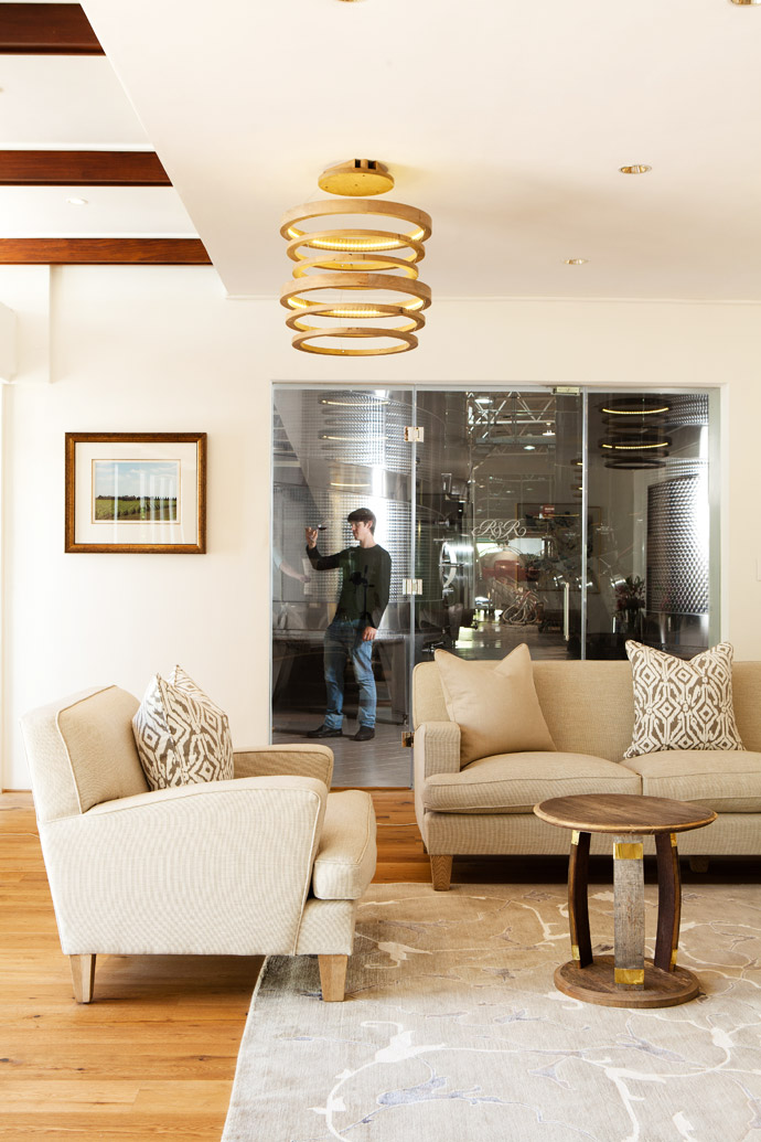 Every piece of furniture here was custom-made for Rupert & Rothschild. The side table with its brass detail and the hanging lamp imitate the shape of a wine barrel. The rug is from Gonsenhausers Fine Rugs. 
