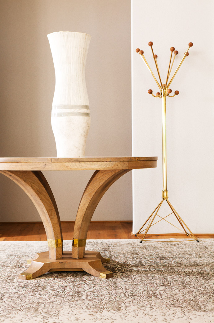Christo designed the coat stand, which is clad in brass and has wooden knobs. The table with its brass detail is also inspired by a wine barrel. The ceramic vase is by artist Helen Vaughan. 