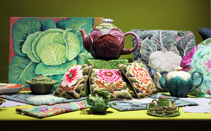 The Victorian ebony glass museum display case, painted to match the green room, features a collection of Kaffe’s vegetable-inspired miniature needlepoint cushions, and cabbage and cauliflower ceramics. 
