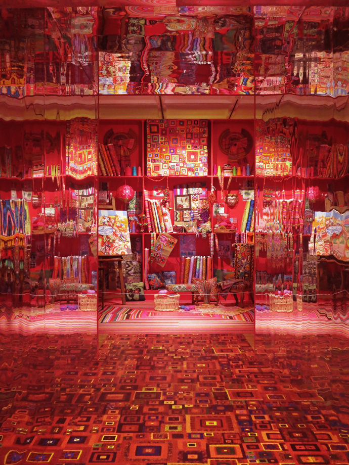 A mirrored tunnel leads visitors into the first exhibition space, the recreation of Kaffe’s studio, reflecting the dazzling colours of his work.