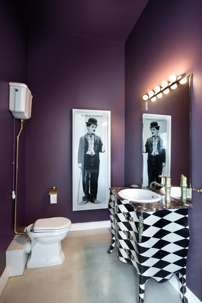 A harlequin washstand, Charlie Chaplin print and purple walls add an eclectic touch.
