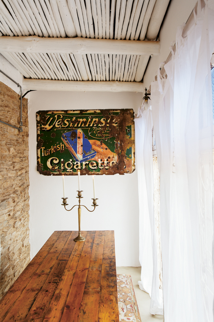 The Pharo family’s old table and Cuban candelabra perfectly suit the elongated space of the enclosed stoep. They found the 1950s cigarette ad in Prince Albert and bought the benches at the vintage decor shop Nerf-af. 
