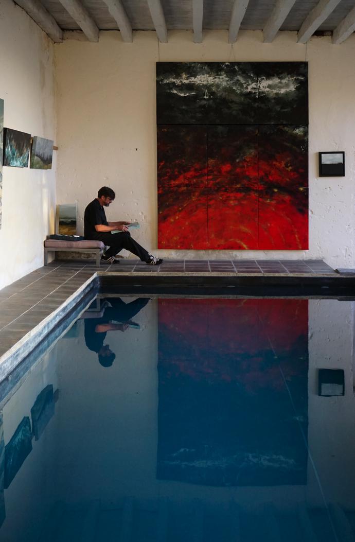 Olivier hanging his exhibition “Comme se Taisent les Nuages” around the pool at Aux Jardins des Thévenets.