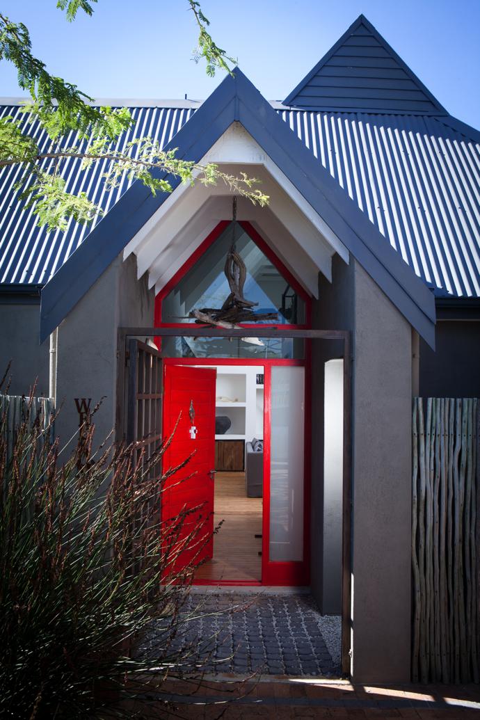 The bright red front door is flanked by indigenous thatching reed planted by Cornel. 
