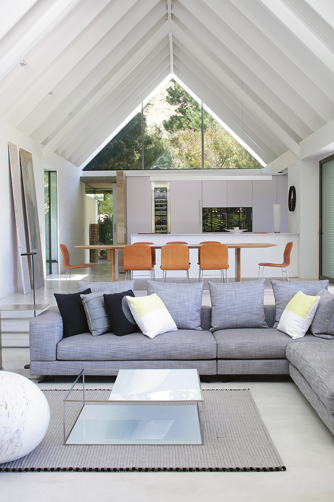 The brief was for a clutter-free, simple home. Piers added warmth with wool rugs from Stockholm, a sofa from Minotti, a Ronel Jordaan rock cushion, and bespoke side and occasional tables in stainless steel and glass.