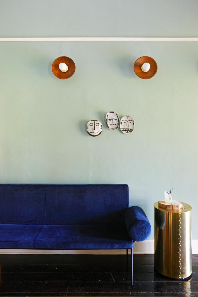The masks are by Clementina Ceramics, the sofa was custom-made by Guideline, and the wall-mounted lights and brass table are from Studio No 19.