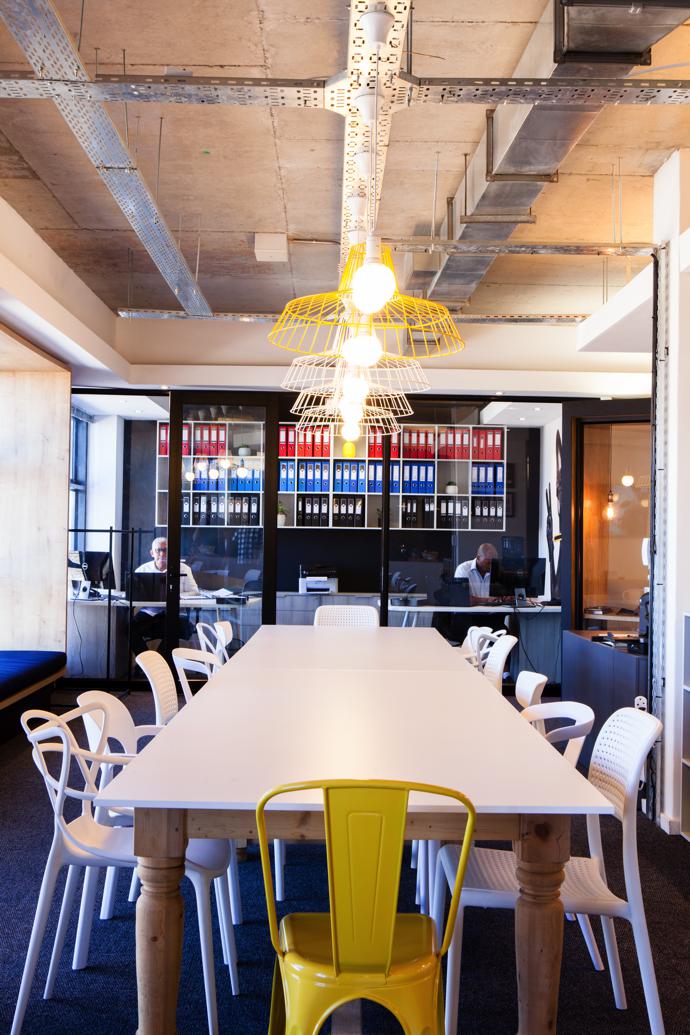 A pine table with beautiful turned legs from the company’s former Woodstock o ce was freshly fitted with an ice-white PET top. The lights are by Wire World.
