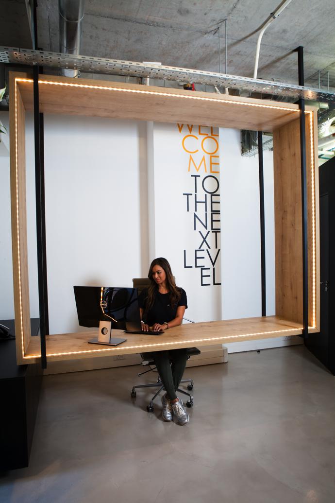 Dee Abrahams at the oak reception counter, which is suspended from the concrete slab above by matt black steel brackets.