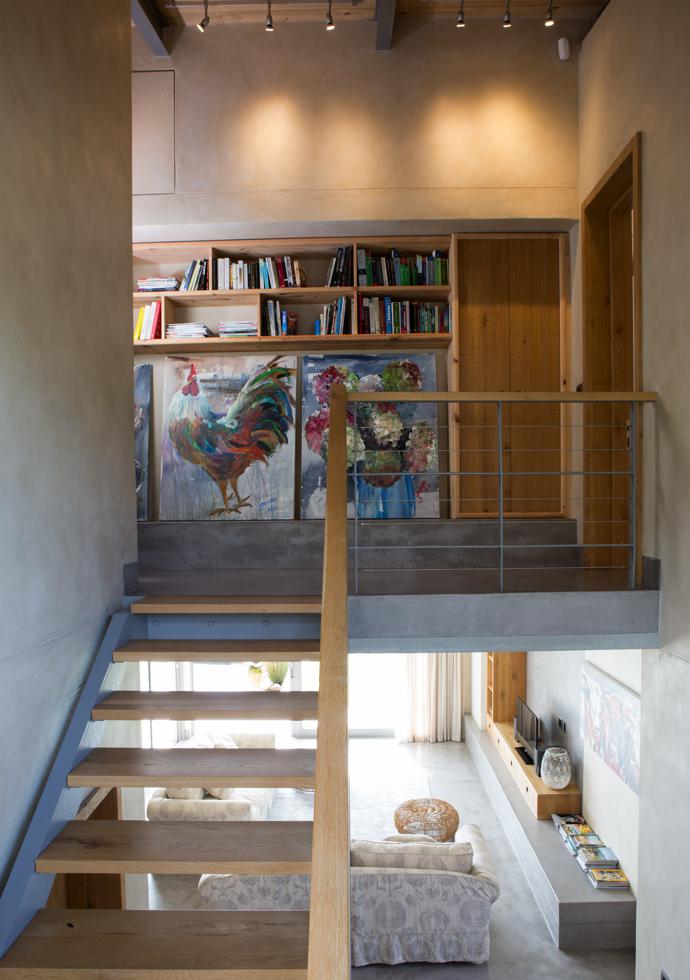 A floating steel-and-timber staircase leads to bedrooms upstairs. The two paintings are by Jeanne Alston from Montagu.