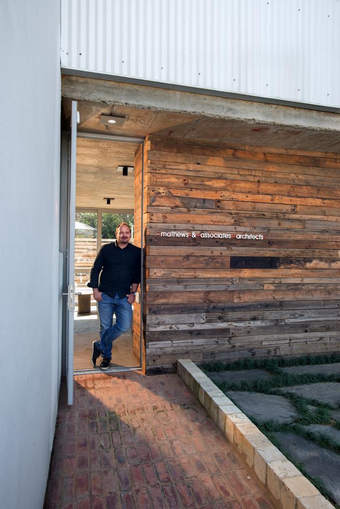 Architect Pieter Mathews, leaning against the wall clad in timber that was originally used for the roof trusses.