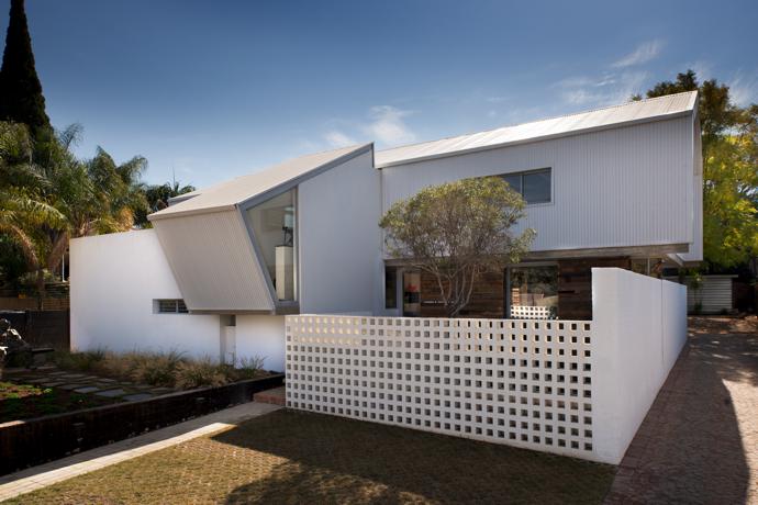A breeze-block wall offers the courtyard light screening from the street. The landscaping in front of the building was done using mostly salvaged plants.