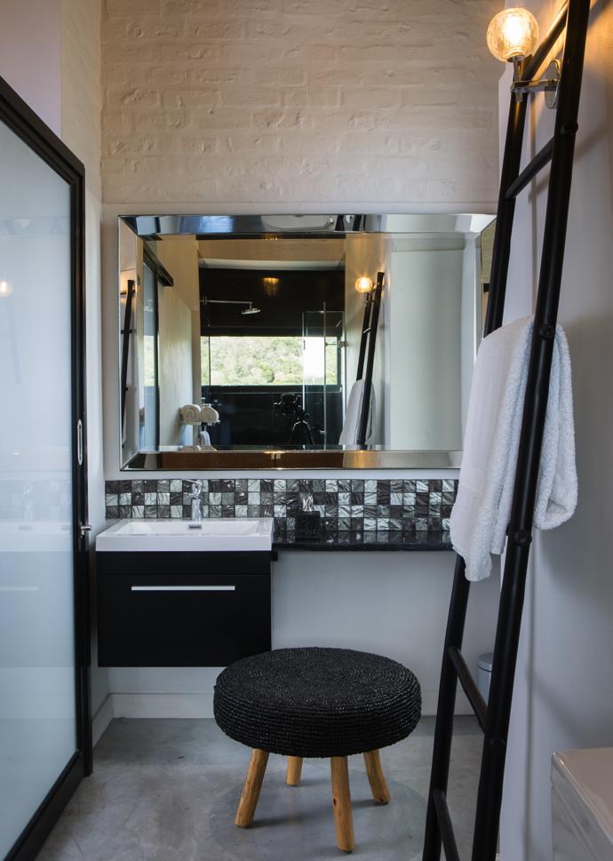 A Venus hand-cut beveled mirror adds dramatic effect to this bathroom. The mirror is from Isabelina and the wood and rattan stool was sourced in the East.