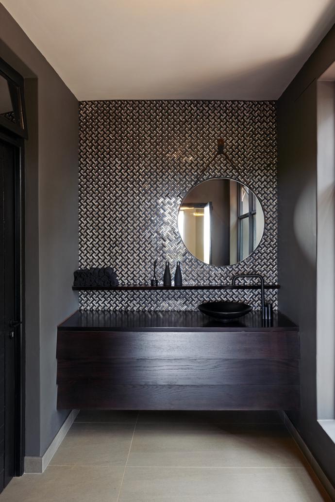 Metallic elements in the bathrooms echo the fireplace surround and bar, and contrast with the rough texture of the slate.