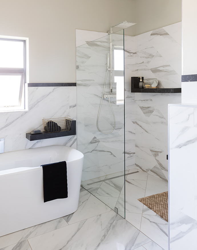 Marble features prominently in the main en-suite bathroom, accented with black, gold and bamboo. The bath and shower are from the Grohe Libra range; thetowels, bathmats and black soap are from Weylandts; and the other bathroom accessories are from H&MHome.