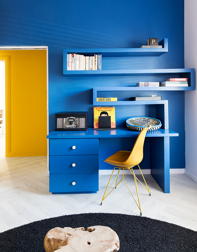 In the study nook, a custom-designed desk unit blends smartly into the Plascon Oceanos (B6-C1-1) wall. Ayellow chair from @home and around black astroturf rug from Belgotex complete the look.