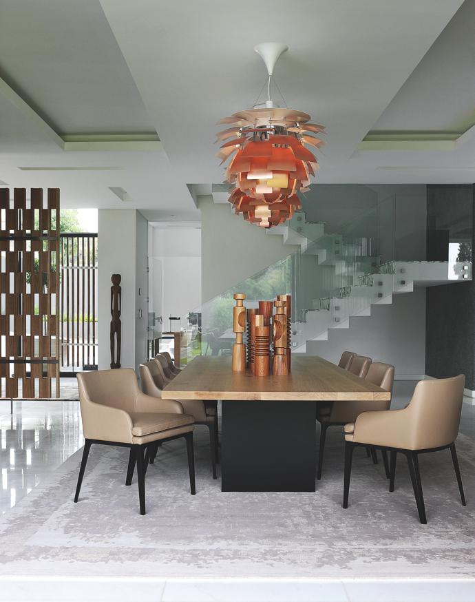 Copper PH Artichoke lamps by Poul Henningsen for Louis Poulsen hang above the Bison dining room table and customised Oscar Elegante dining chairs from OKHA. The Reflect mirror, Omega server and Revolve lamps are also all from OKHA. 