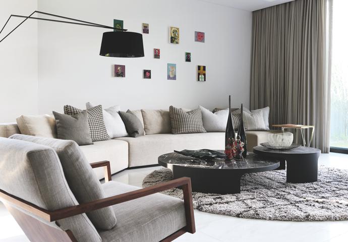 The coffee tables in the family lounge were custom designed by OKHA. Powder‐coated steel legs with acid‐etched and sand‐blasted marble tops come together as two separate yet connected circular spheres that allow the contoured Zeppelin sofa, also OKHA, to mimic their fluid edges. The STM Swivel armchair, To Be One Standing lamp, David Reade Glassware and custom-designed rug are all OKHA. 