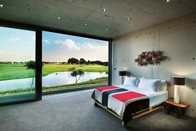 Spectacular views onto the 10th and 18th holes can be had from all the bedrooms. In this bedroom, a wooden Weylandts bed base is teamed with a bright blanket and metal wall art, also from Weylandts.