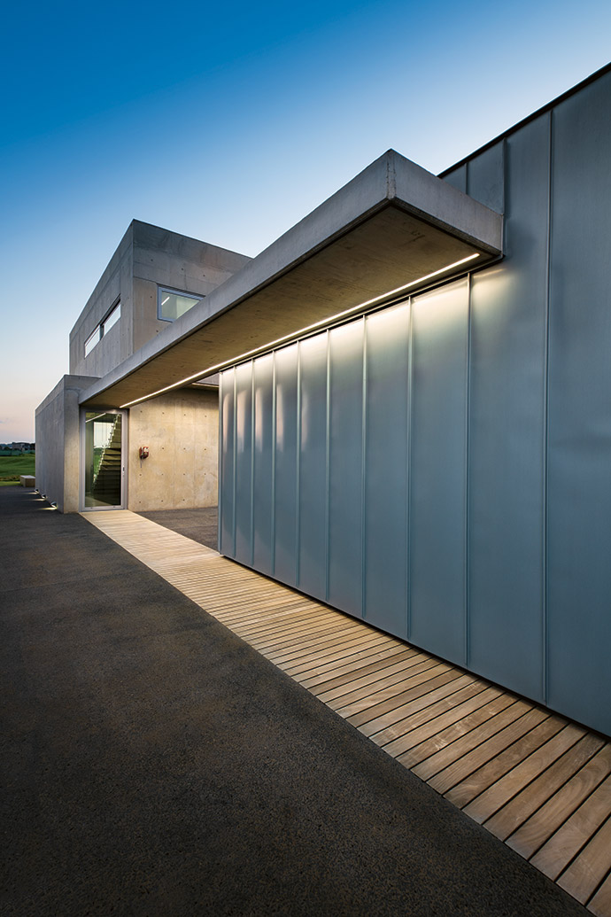 North light floods the passage through sliding windows and frosted-glass doors to each of the bedrooms. All plumbing and wiring are concealed behind steel panels.
