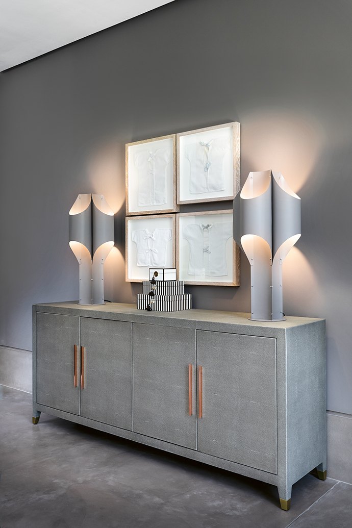 Table lamps from Restoration Hardware in the US sit atop a Graydon Shagreen Collection bureau (also from Restoration Hardware in the US), flanking framed birthgowns of the owner’s four children.