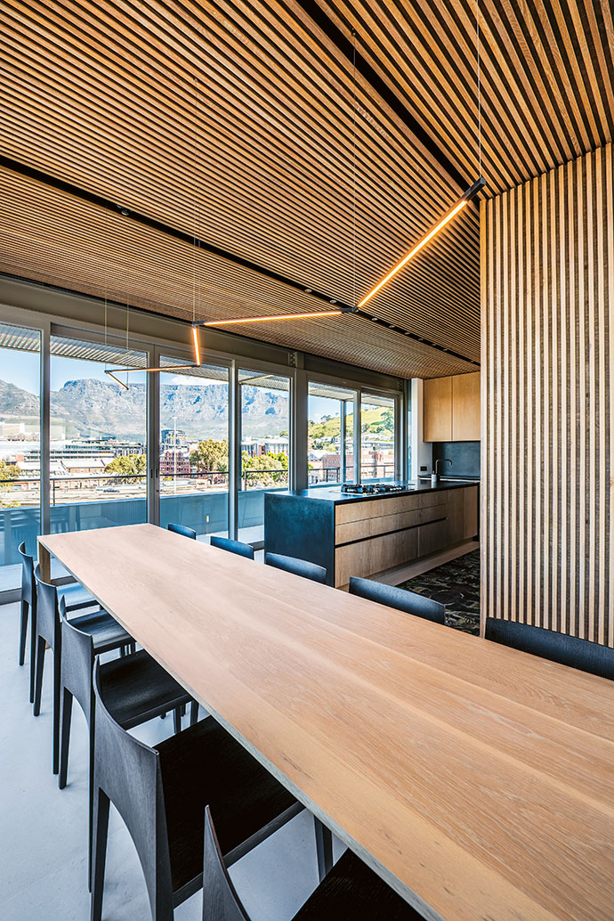Matte-black surfaces, furniture and accessories are offset by the light wooden slats and modern light fixtures.