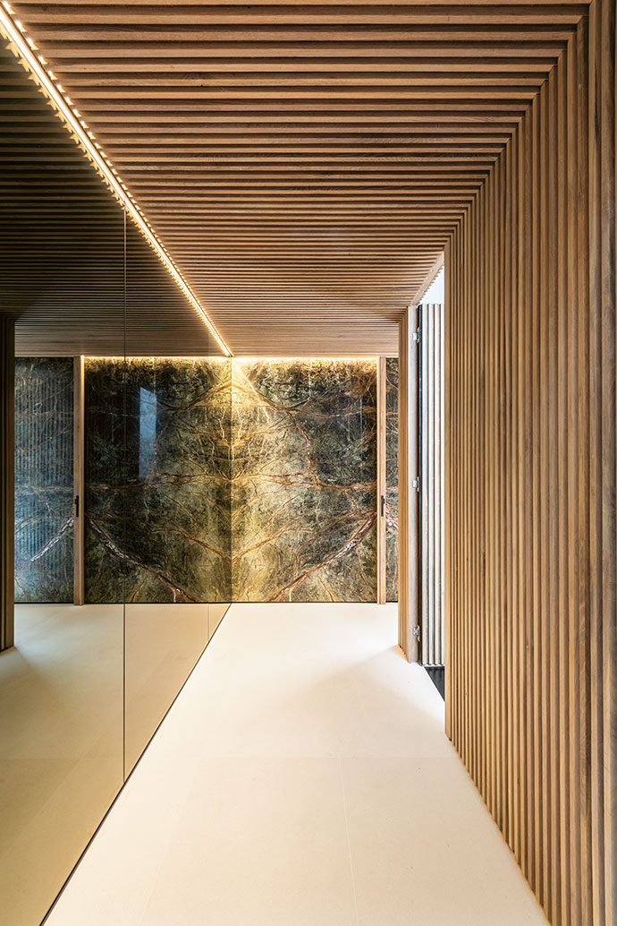 In the foyer, a subtly moody atmosphere is created by a marble-clad wall and floor-to-ceiling mirrors,
which contrast with the slatted-wood ceiling and wall near the stairwell.