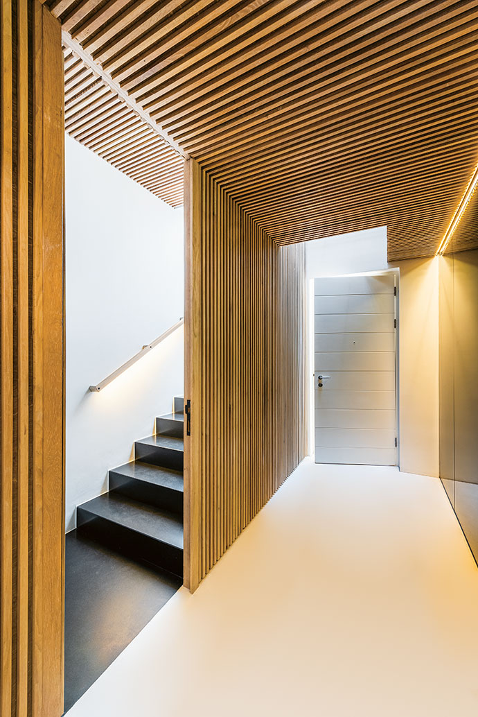 In the foyer, a subtly moody atmosphere is created by a marble-clad wall and floor-to-ceiling mirrors,
which contrast with the slatted-wood ceiling and wall near the stairwell.