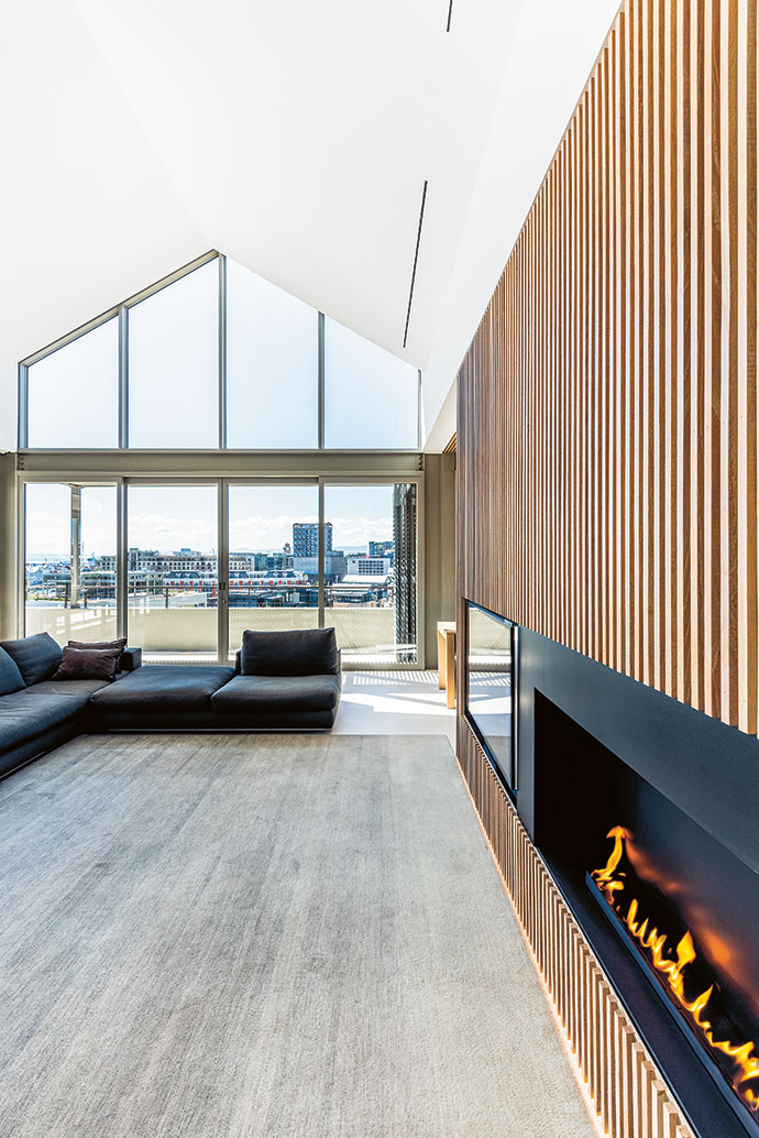At the heart of the home is a light-filled living room with a contemporary fireplace and TV embedded in the slatted wall.
