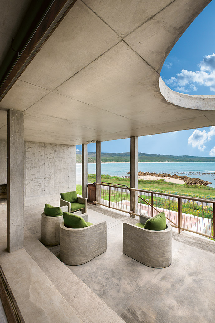 The concrete chairs on the shaded veranda are both cool and functional, providing a vantage point from which to observe the changing moods of the ocean.