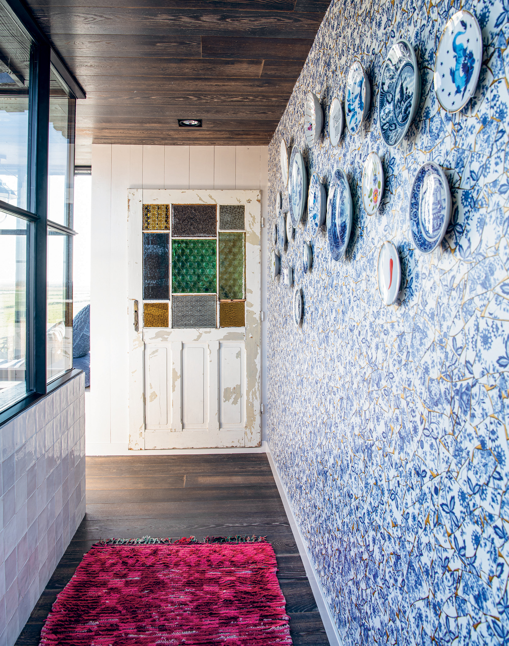 Delft blue wallpaper provides a backdrop for a collection of ornamental plates, many of which once belonged to Eleonora’s grandmother. The vintage door was sourced at an architectural salvage store.