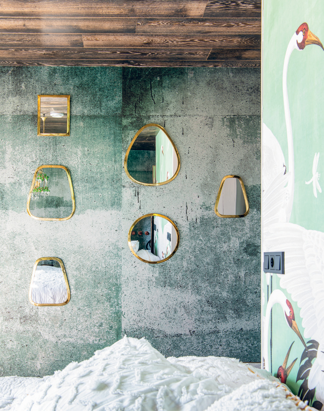 A collection of mirrors reflects the green tones of the master bedroom.