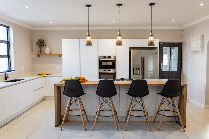 Inside Living designed and installed this modern kitchen in this homely house with its family friendly and accommodating layout. The kitchen is in all white with black details & accessories such as the shelf brackets and sink mixers. The kitchen is fitting for seating for a quick meal or planning a large family meal.