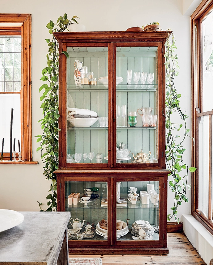 A glass armoire with wooden backing painted green displays a collection of treasures from the decor store previously owned by Sanet and her studio partner Rupert Smith
