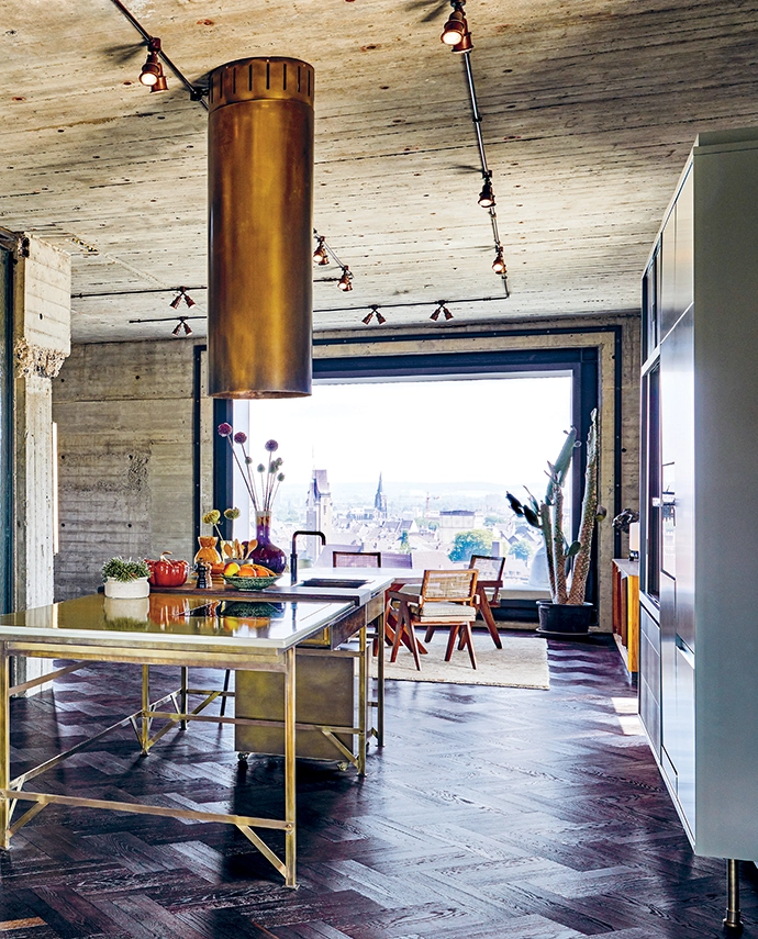A modern take on a kitchen island – with a brass frame and enamelled lava stone countertop designed by Eginstill in collaboration with Nicemakers – sits under a custom Eginstill hood. The pivoting glass doors, also a Nicemakers design, were manufactured by Soons Interieurbouw, and the Eiffel wall light is from Frama.