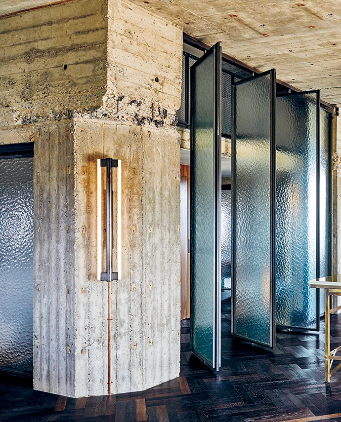 A modern take on a kitchen island – with a brass frame and enamelled lava stone countertop designed by Eginstill in collaboration with Nicemakers – sits under a custom Eginstill hood. The pivoting glass doors, also a Nicemakers design, were manufactured by Soons Interieurbouw, and the Eiffel wall light is from Frama.