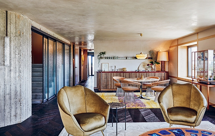 A reception area on the ninth floor includes spaces for dining and lounging, with a vintage marble-top table surrounded by Warren Platner chairs from Knoll, a glass display cabinet by Svenskt Tenn that holds a collection of glassware and serveware, and an Alfred sofa from Flexform and reupholstered vintage chairs offering comfortable seating options.