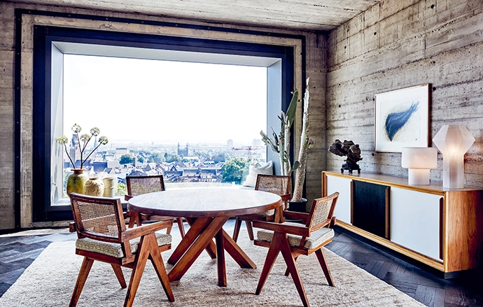 The breakfast nook next to the kitchen, with a Pierre Chapo table and four Pierre Jeanneret chairs, makes the most of the custom picture window designed by Nicemakers and manufactured by Trimet.