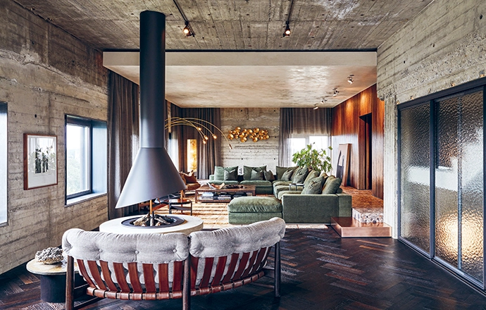 A sculptural fireplace, with a travertine platform designed by Nicemakers, takes centre stage in the open living space that flows from the dining area.