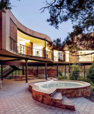 In response to an existing dry riverbed, and to minimise site impact, Kloof House is elevated, revealing a gracefully curved facade that opens to the natural tree canopy.