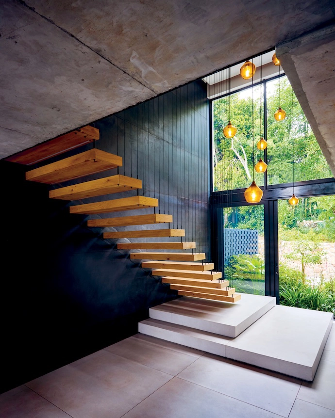 A constellation-like hand-blown glass light fitting adds softness to the geometric planes of the double-volume entrance hall. 