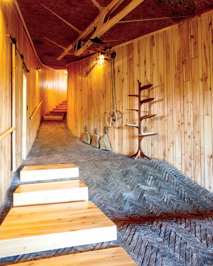 Against the wall is a Leaf bookshelf by Meyer Von Wielligh. The bespoke wind-up ceiling fan works with a grandfather clock-like mechanism of suspended rocks hanging on cables.