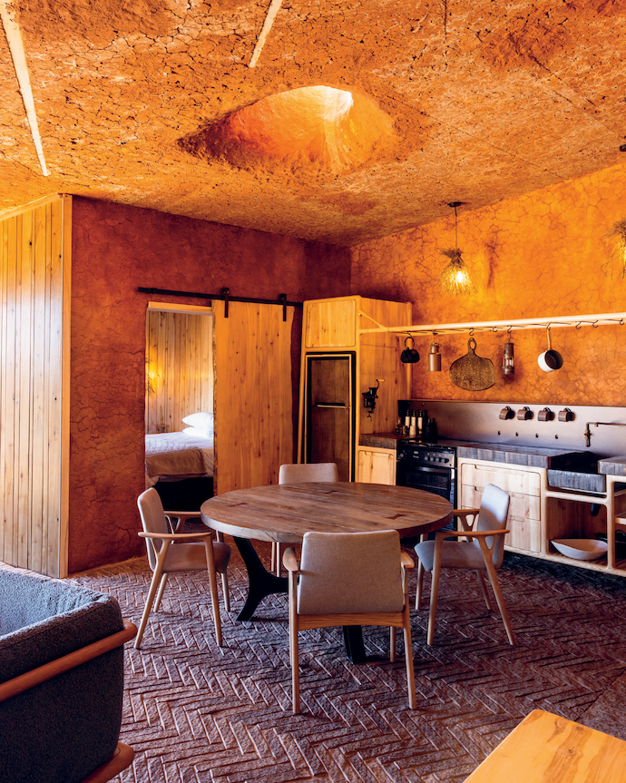 The bespoke kitchen and barn door by Meyer Von Wielligh are made from poplar, an invasive species that commonly grows in Karoo riverbeds. The cracked mud plaster on the walls is from a nearby dam, with the patinaed cracks controlled by the ratio of river sand to mud.