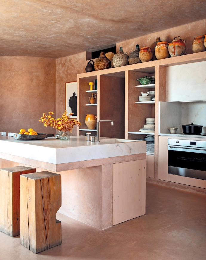 Like the rest of the house, the kitchen is coated in floor-to-ceiling plaster, with custom shelving for the oven and hob.