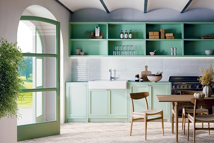 A tranquil feel is achieved here with soft sage-green cupboards, open shelving and natural light streaming in through a large arched door. The brick-stacked tile backsplash adds texture and brightness, and is balanced beautifully by the herringbone pattern of the Nolita flooring in Mud by Decobella.