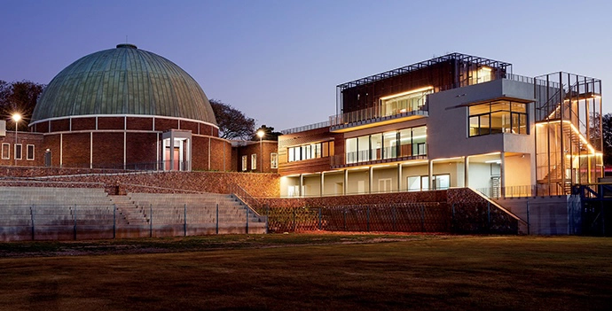 The original building and the new extension complement one another visually, but remain distinct. Seating for the Bidvest Stadium, also part of this project, has been integrated, and is visible in front of the dome.