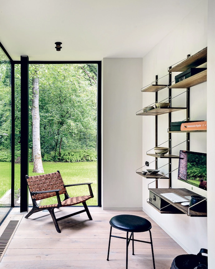 A compact office space is equipped with a modular Frama Shelf Library system.